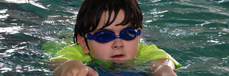 kid wearing goggles swimming in pool